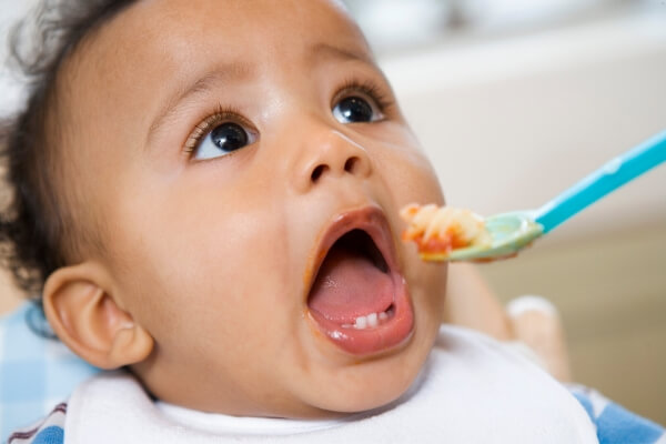 baby being fed spoonful of spaghetti