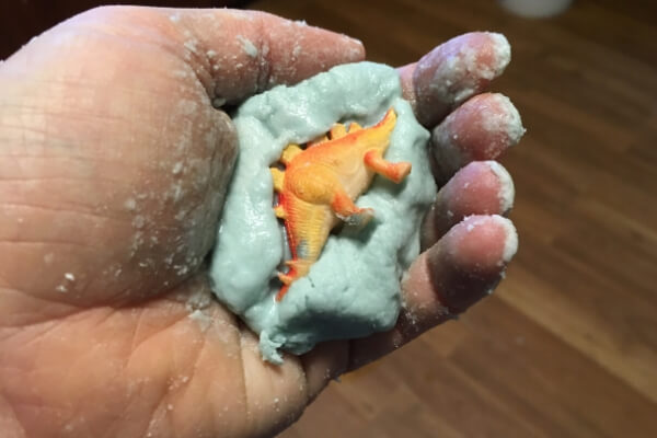 baking soda eggs being formed around a tiny toy dinosaur