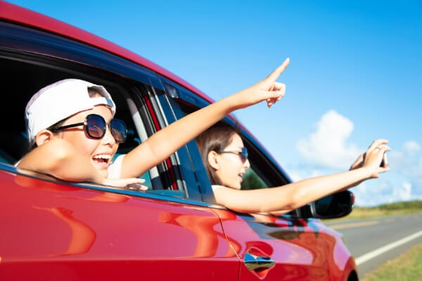 girl pointing out of car with mom on a road trip