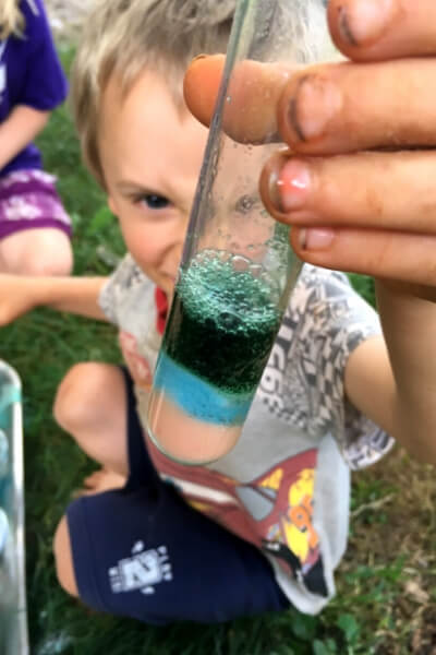 boy holding up a test tube of multicolored baking soda and vinegar mixtures
