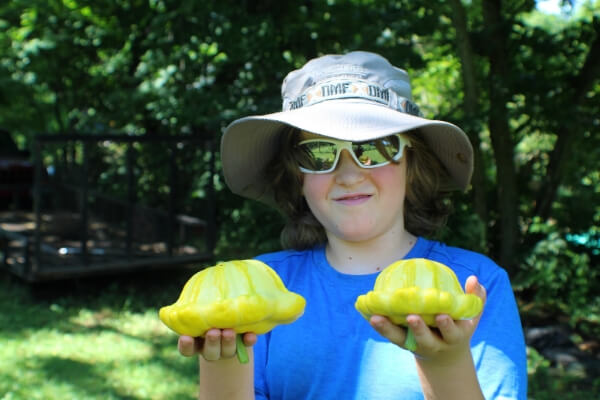 teen boy holding 2 fresh picked yellow squash