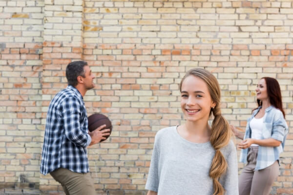 teen girl playing basketball with her mom and dad