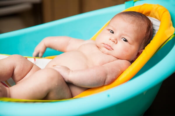 infant in a baby bath tub sling