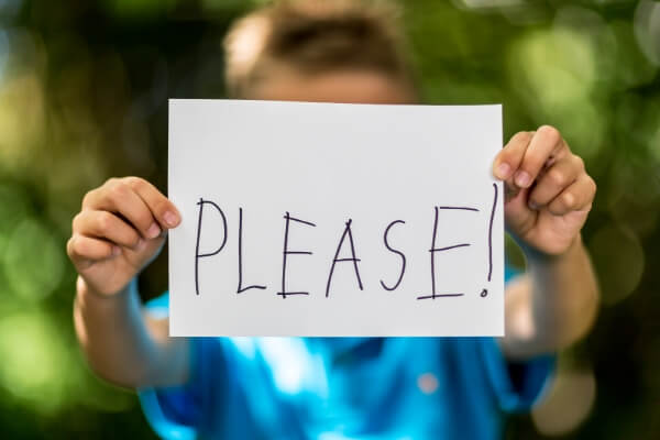 young boy holding a sign that says please
