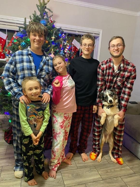 5 kids in christmas pajamas in front a christmas tree