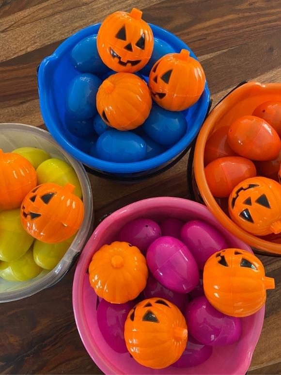 halloween buckets filled with colored eggs and pumpkins for an egg hunt