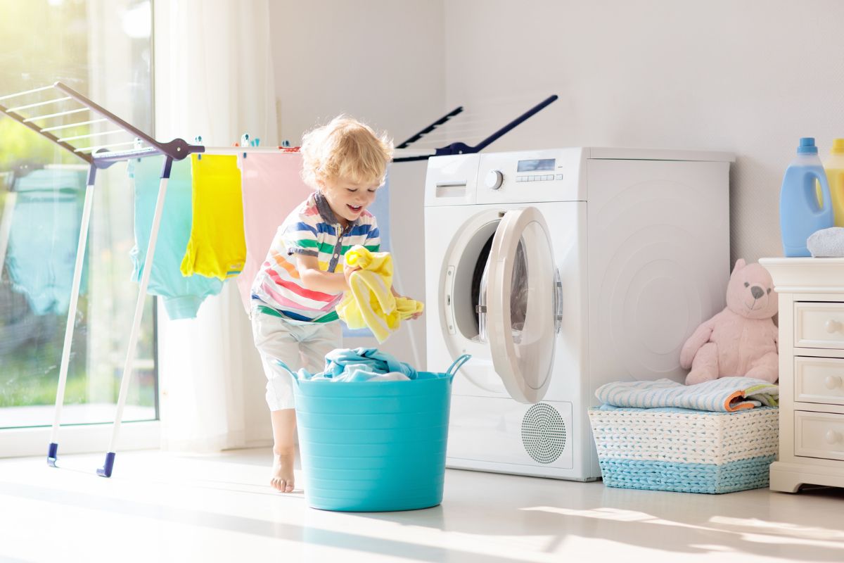 toddler taking clothes out of the drier and putting them in a basket