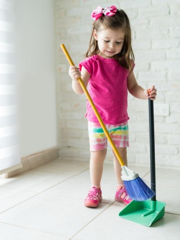 toddler girl sweeping with small broom and dustpan